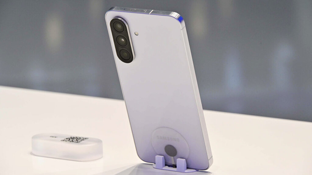 Traseira do Galaxy A56 em uma bancada; o celular tem um módulo de câmeras com três lentes agrupadas em uma lombada única