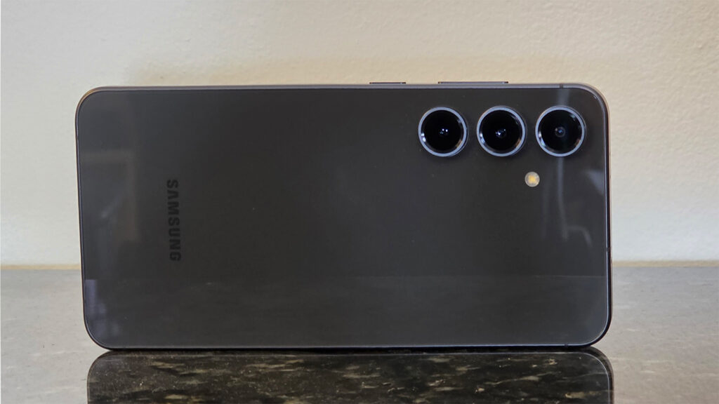 A tampa traseira do Galaxy S24 FE na cor grafite, com as três câmeras na parte superior