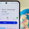 Foto de um celular com a página do Signal na Play Store ao lado de um globo mostrando a região do Oriente Médio