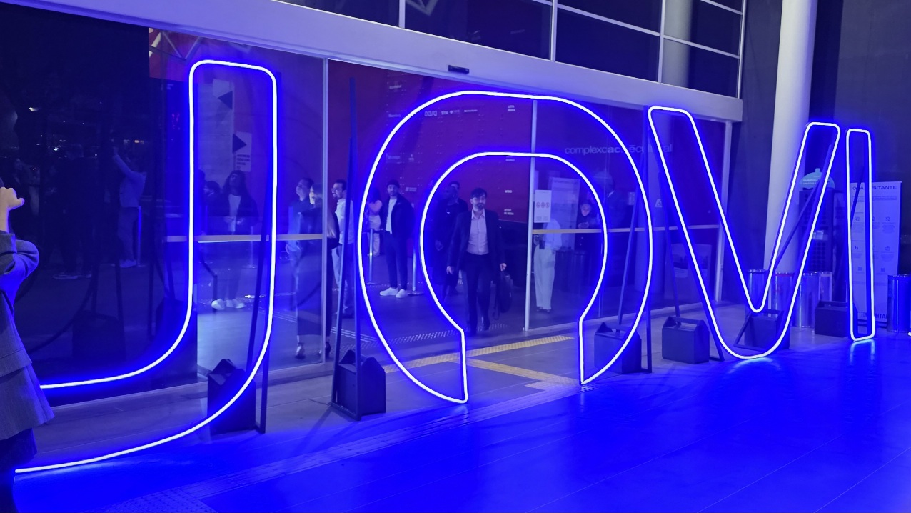 Logo da Jovi em neon na entrada de um estabelecimento. As letras estão na cor azul