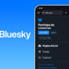Montagem do logo da rede social Bluesky, com a borboleta na cor branca sobre um fundo gradiente azul, e um celular com a tela inicial do app