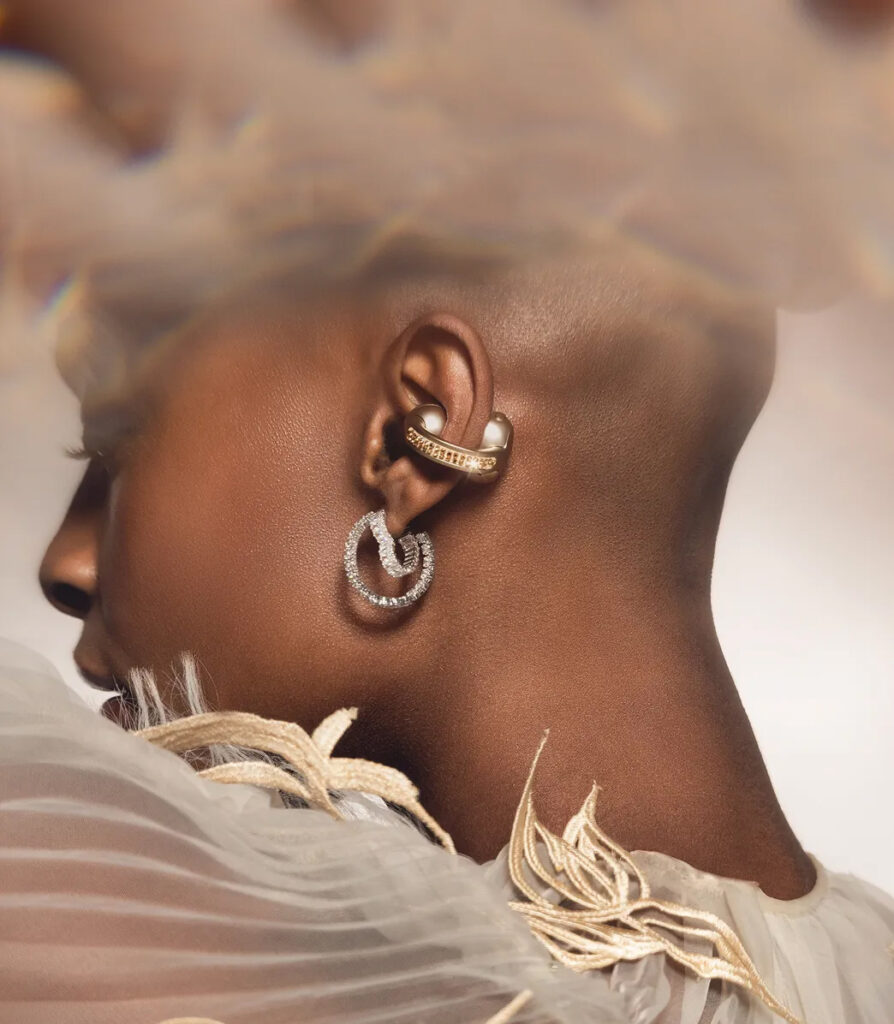 Imagem do fone de ouvido Moto Buds Loop no ouvido de uma mulher de cabelo raspado. Ela usa um brinco, além do fone, que também parece uma joia com cristais incrustados