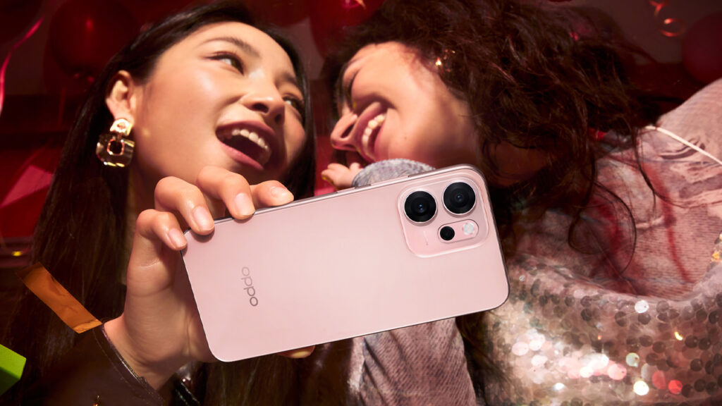 Oppo Reno 14F na cor rosa nas mãos de uma moça que conversa com uma amiga