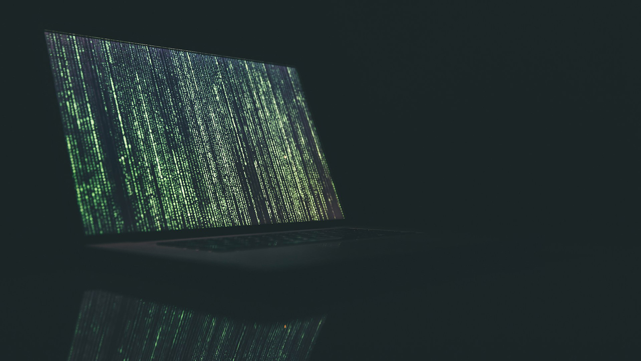 Notebook com uma tela estilo Matrix, com códigos em verde na tela