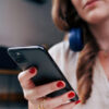 Uma pessoa com fone de ouvido no pescoço olha para a tela do celular