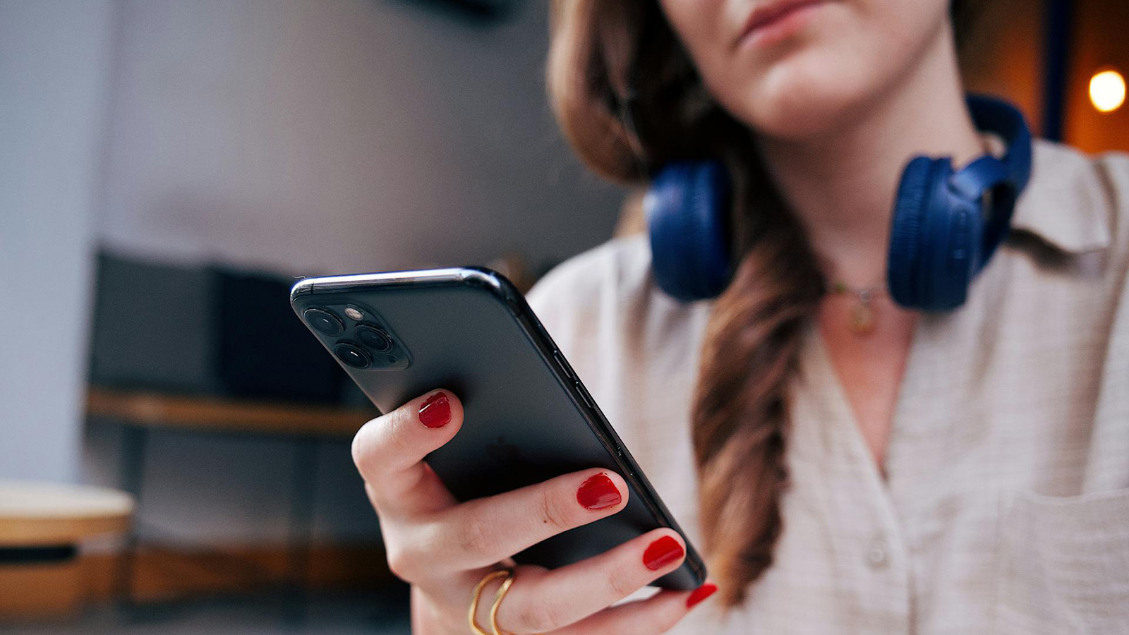 Uma pessoa com fone de ouvido no pescoço olha para a tela do celular