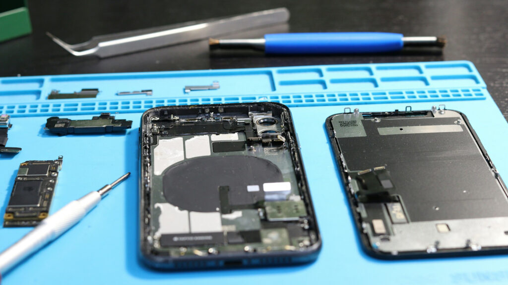 Uma bancada de reparo com ferramentas e um celular aberto para trocar a bateria