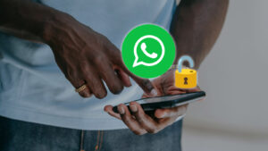 Uma pessoa segura um celular com o ícone do WhatsApp e um cadeado aberto acima da tela