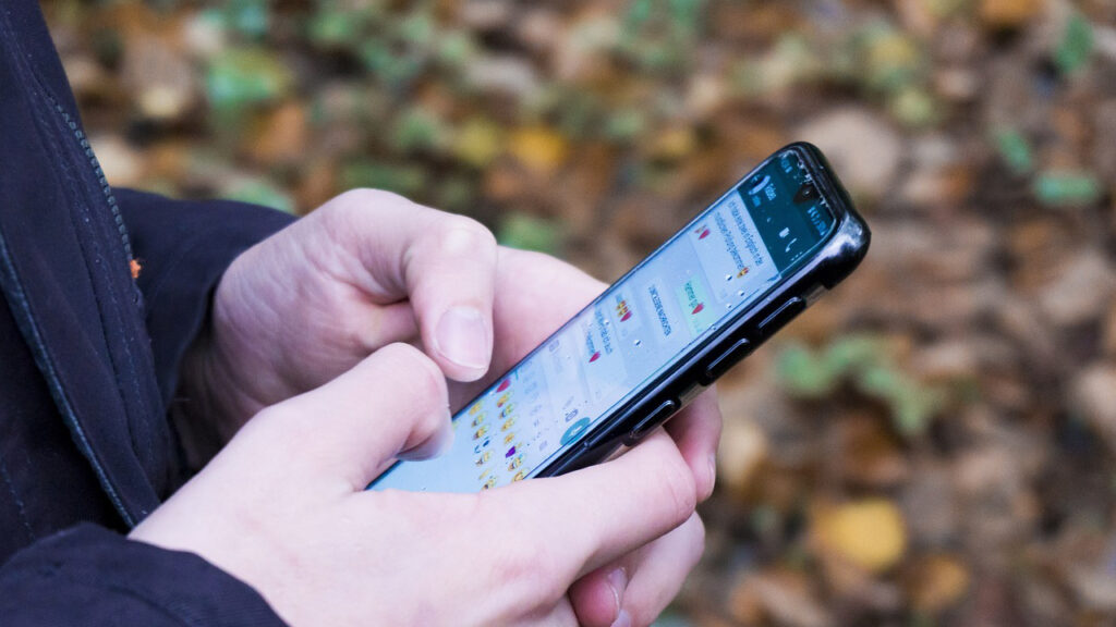 Pessoa segura o celular em uma tela de conversa do WhatsApp