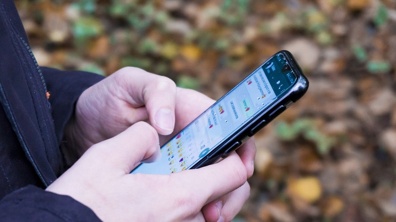 Pessoa segura o celular em uma tela de conversa do WhatsApp